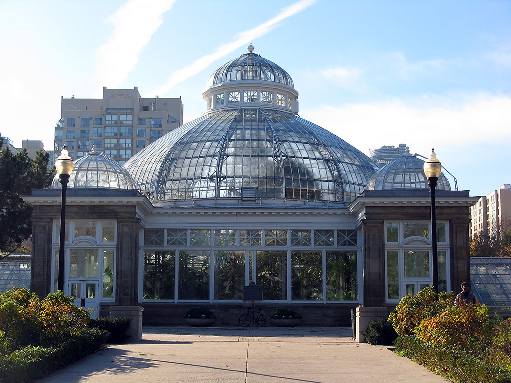 The glass exterior of a conservatory lit from within at dusk
